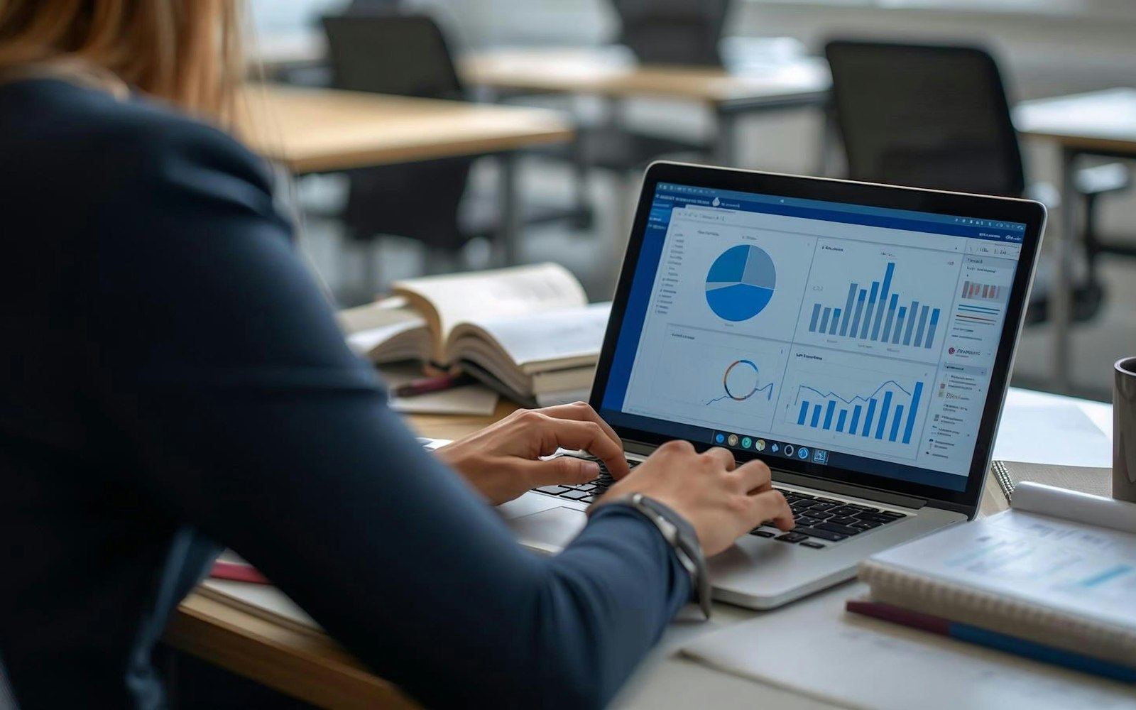 Persona trabajando en una laptop con paneles de datos y gráficos, representando la digitalización de procesos.